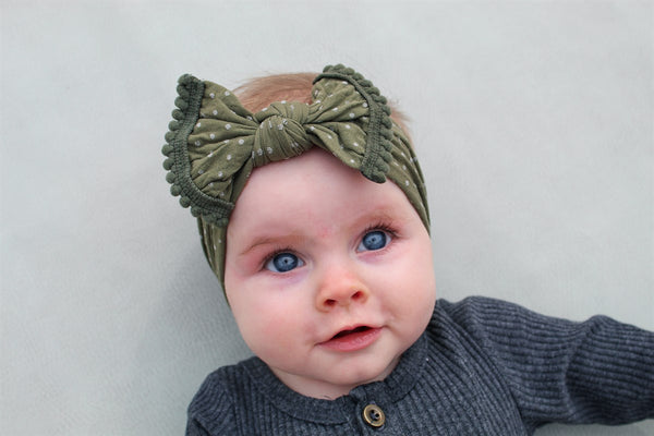 baby Girl in Olive Swiss Dot Pom Pom Nylon Headbands - Golden Dot Lane