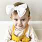 Baby in White Dottie Knottie Bows - Golden Dot Lane